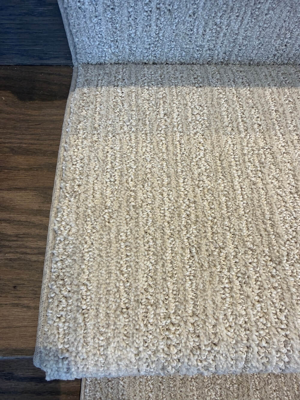 Sewn-edge binding on beige stair runner over hardwood