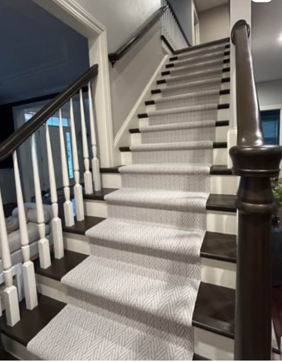 Staircase with white carpet and wooden railings in a home interior.