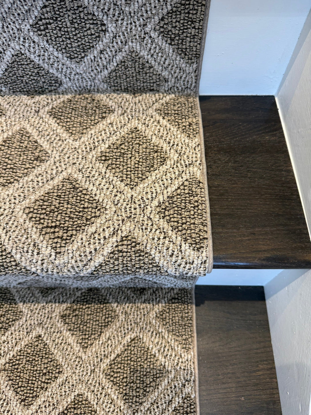 Patterned stair runner on a staircase with a neutral color scheme.