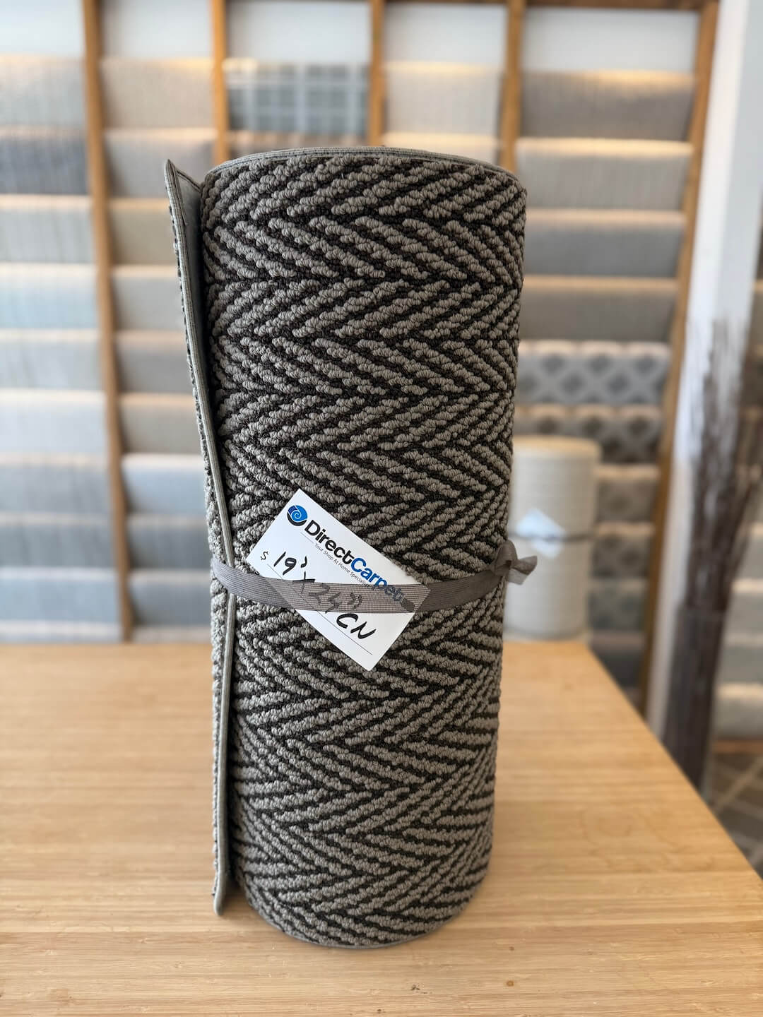 Roll of gray fabric with a label on a wooden surface