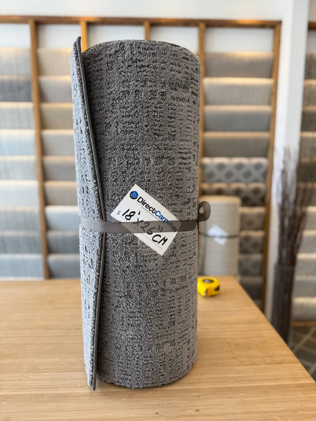 Roll of gray carpet on a wooden table with a blurred background