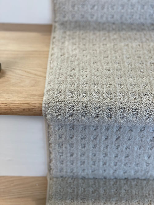 Gray textured carpet on a wooden staircase