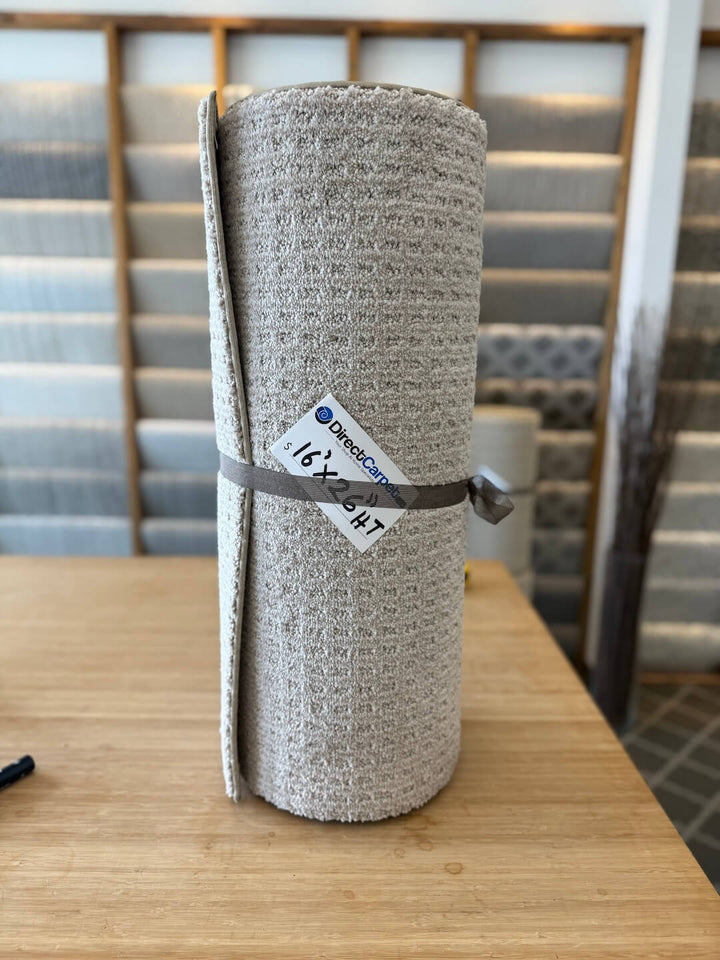 Rolled-up gray rug with a label on a wooden table