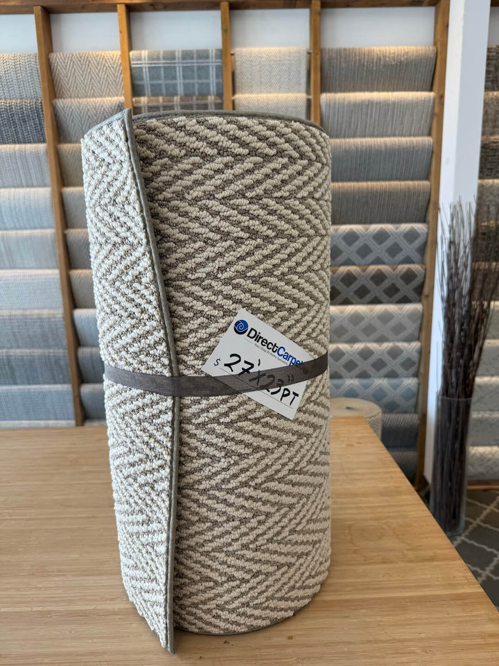 Roll of patterned carpet with Direct Carpet label in a showroom setting